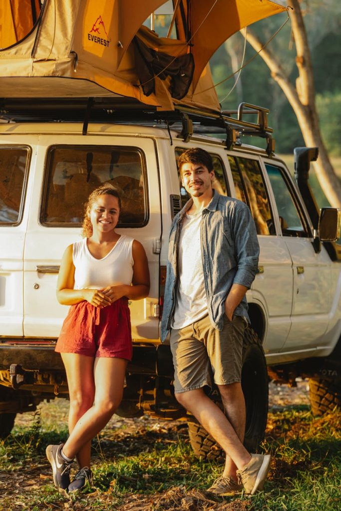 Smiling couple enjoying a road trip in nature with an SUV equipped with a rooftop tent.
